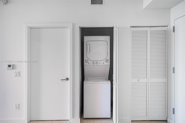 clothes washing area with stacked washing maching and dryer