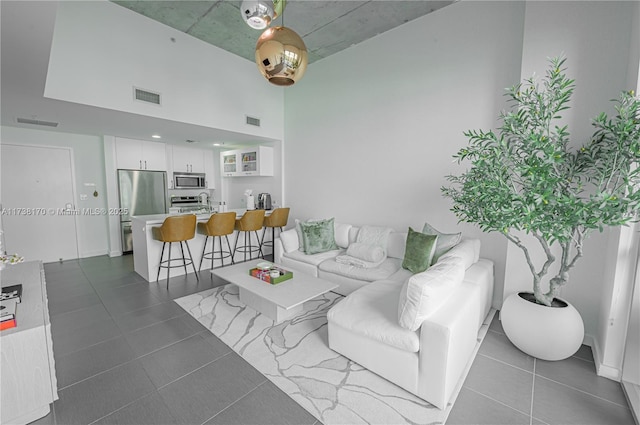 living area featuring dark tile patterned floors, a high ceiling, and visible vents