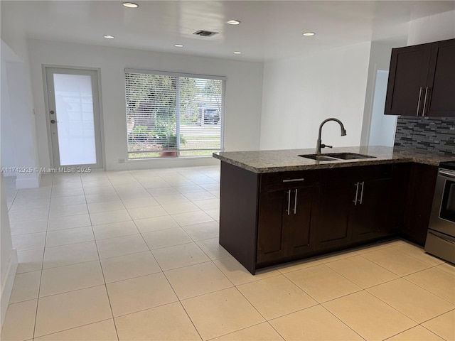 kitchen featuring sink, stone countertops, kitchen peninsula, stainless steel electric stove, and decorative backsplash