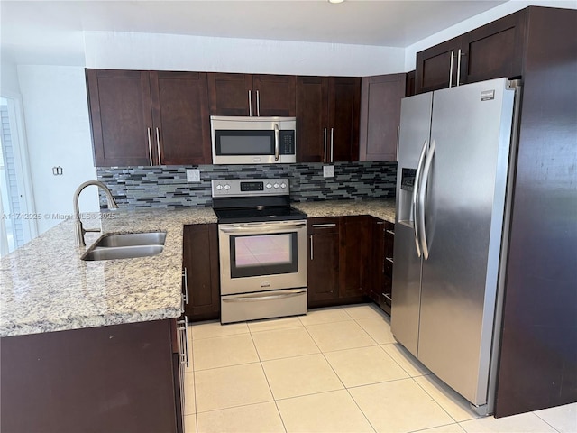 kitchen with sink, light stone counters, kitchen peninsula, stainless steel appliances, and backsplash