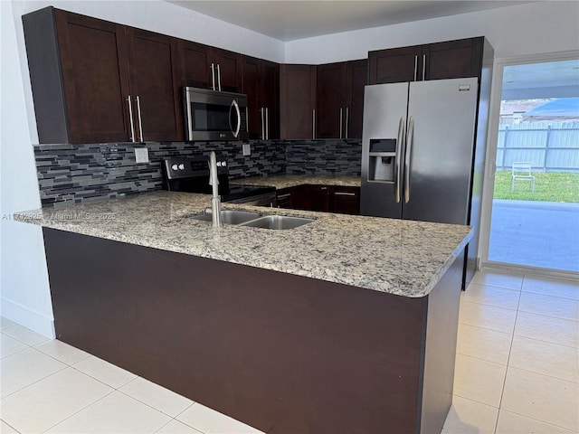 kitchen featuring light tile patterned floors, appliances with stainless steel finishes, kitchen peninsula, light stone countertops, and backsplash