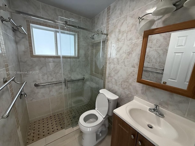 bathroom with a shower with door, vanity, tile walls, and toilet