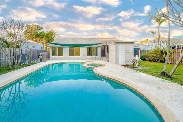 view of pool with a storage shed, a yard, and an in ground hot tub