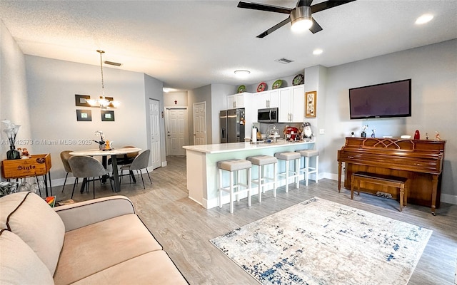 living room with ceiling fan, sink, light hardwood / wood-style flooring, and a textured ceiling