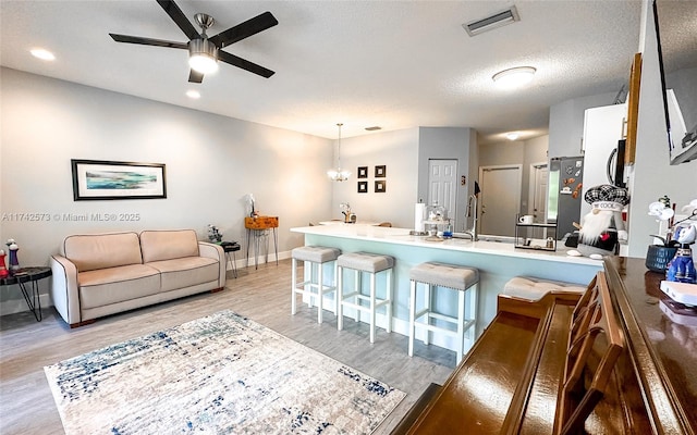 7413 Smithbrooke Dr Unit 7413, Lake Worth, FL 33467 - kitchen with a textured ceiling, light wood-type flooring, a kitchen breakfast bar, kitchen peninsula, and pendant lighting