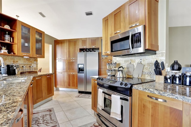 kitchen with appliances with stainless steel finishes, tasteful backsplash, sink, light tile patterned floors, and light stone countertops