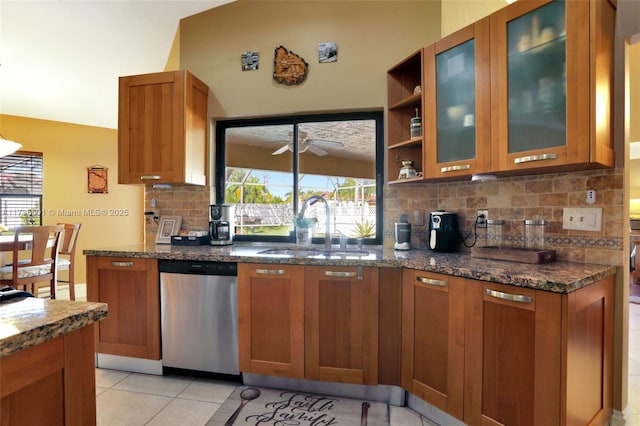 kitchen with dishwasher, sink, ceiling fan, and dark stone counters