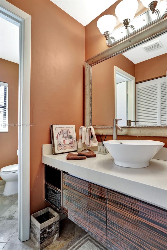 bathroom featuring vanity, tile patterned flooring, and toilet