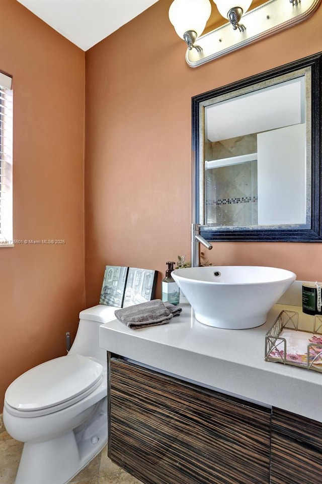 bathroom featuring a shower with door, vanity, and toilet