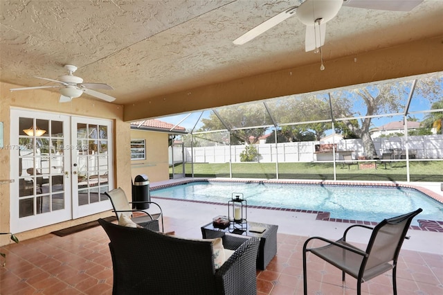 view of swimming pool featuring a lawn, french doors, glass enclosure, ceiling fan, and a patio area