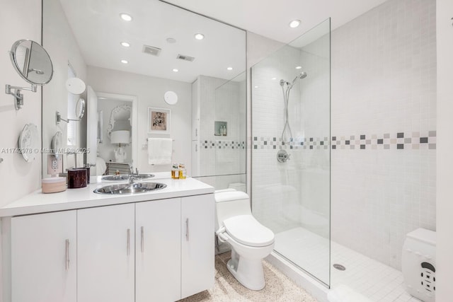 bathroom with tiled shower, vanity, and toilet