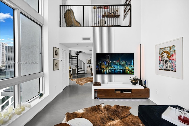 living room with concrete flooring and a towering ceiling