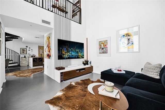 living room featuring concrete floors and a towering ceiling