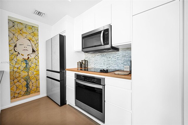 kitchen with white cabinets, wood counters, stainless steel appliances, and decorative backsplash