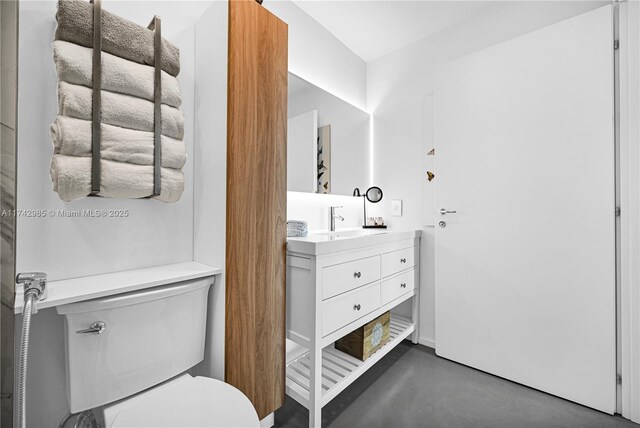 bathroom with concrete flooring, vanity, and toilet