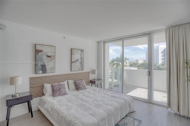 bedroom featuring floor to ceiling windows, light hardwood / wood-style floors, and access to outside