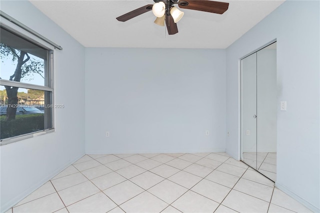 tiled spare room featuring ceiling fan