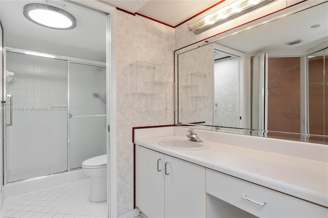 bathroom with vanity, a shower with shower door, tile patterned floors, and toilet