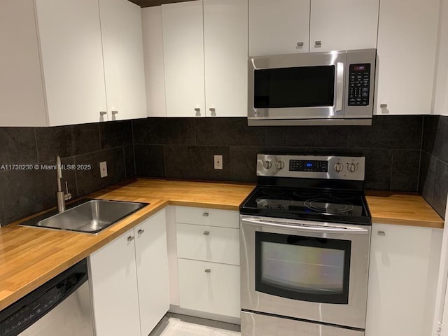 kitchen featuring white cabinetry, stainless steel appliances, and wooden counters