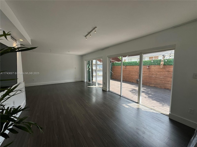 unfurnished living room with rail lighting and dark hardwood / wood-style flooring