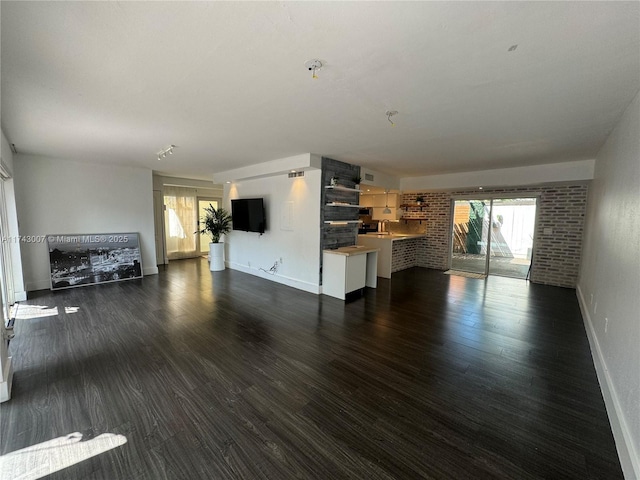 unfurnished living room featuring dark hardwood / wood-style flooring and brick wall