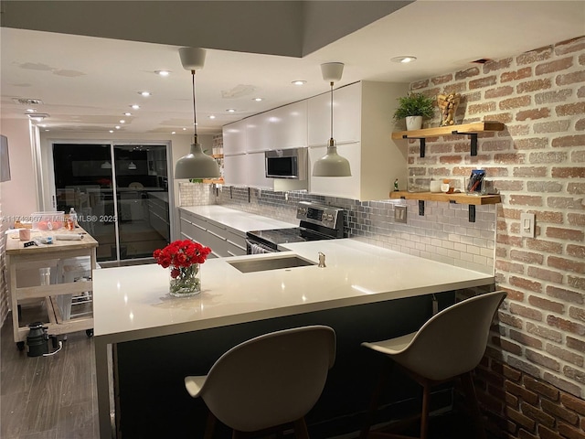 bar featuring stainless steel electric stove, pendant lighting, a kitchen bar, and kitchen peninsula