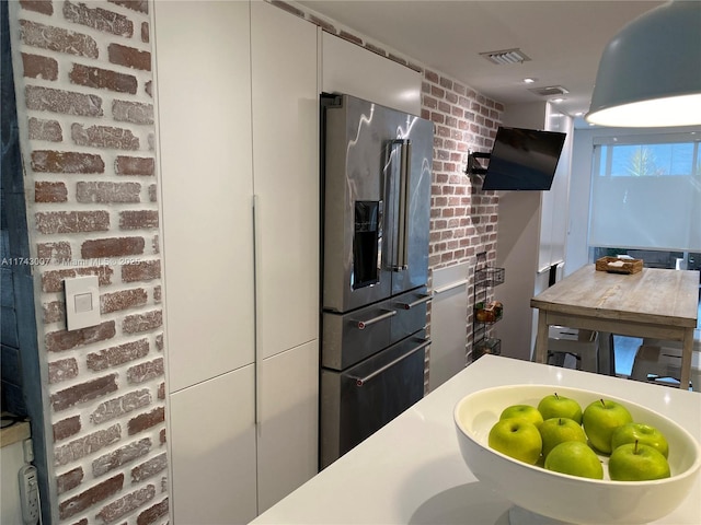 kitchen with high quality fridge, brick wall, and white cabinets