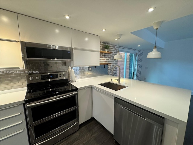 kitchen with pendant lighting, sink, stainless steel appliances, white cabinets, and kitchen peninsula