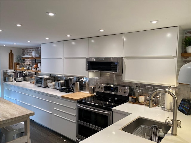 kitchen featuring backsplash, appliances with stainless steel finishes, sink, and white cabinets