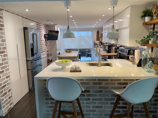 kitchen featuring white cabinetry, decorative light fixtures, appliances with stainless steel finishes, a kitchen breakfast bar, and kitchen peninsula