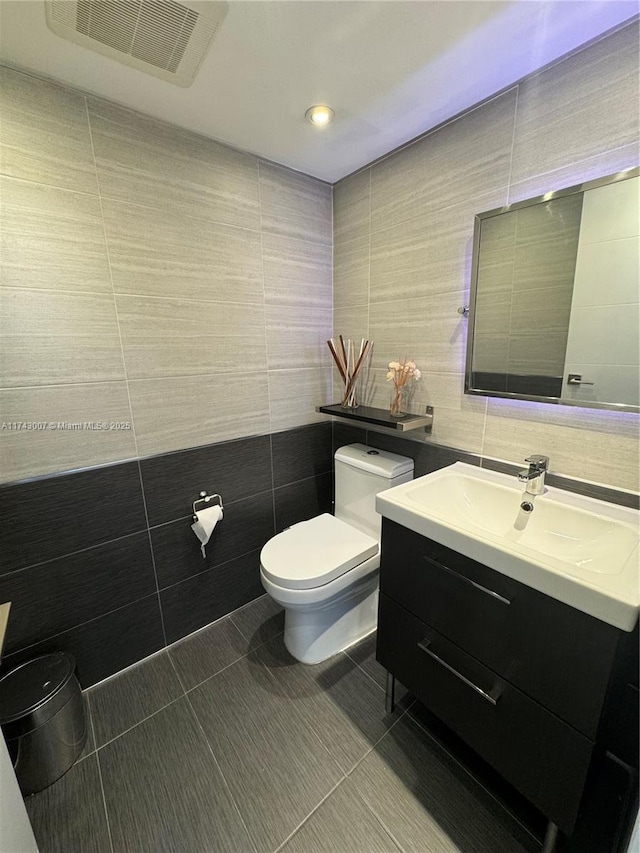 bathroom with tile walls, vanity, tile patterned floors, and toilet