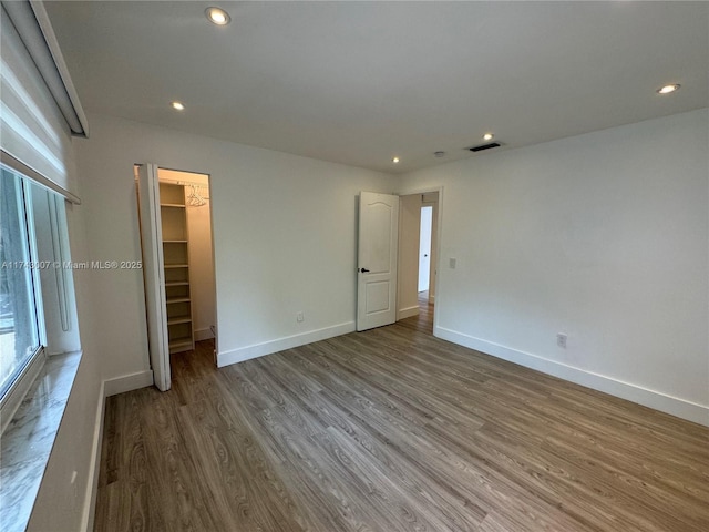 unfurnished bedroom featuring hardwood / wood-style flooring, a spacious closet, and a closet