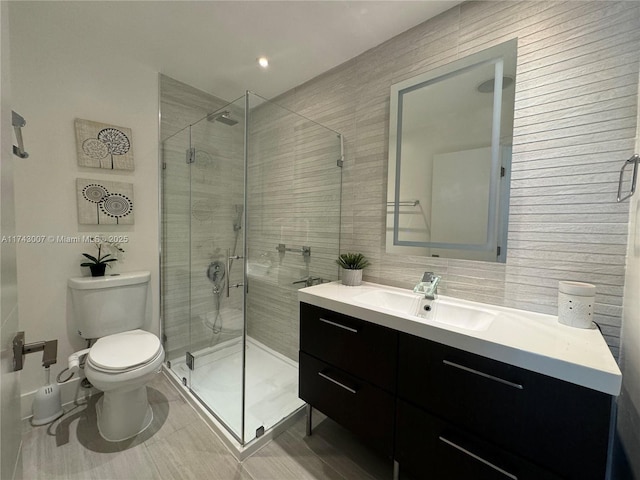 bathroom featuring a shower with door, vanity, and toilet