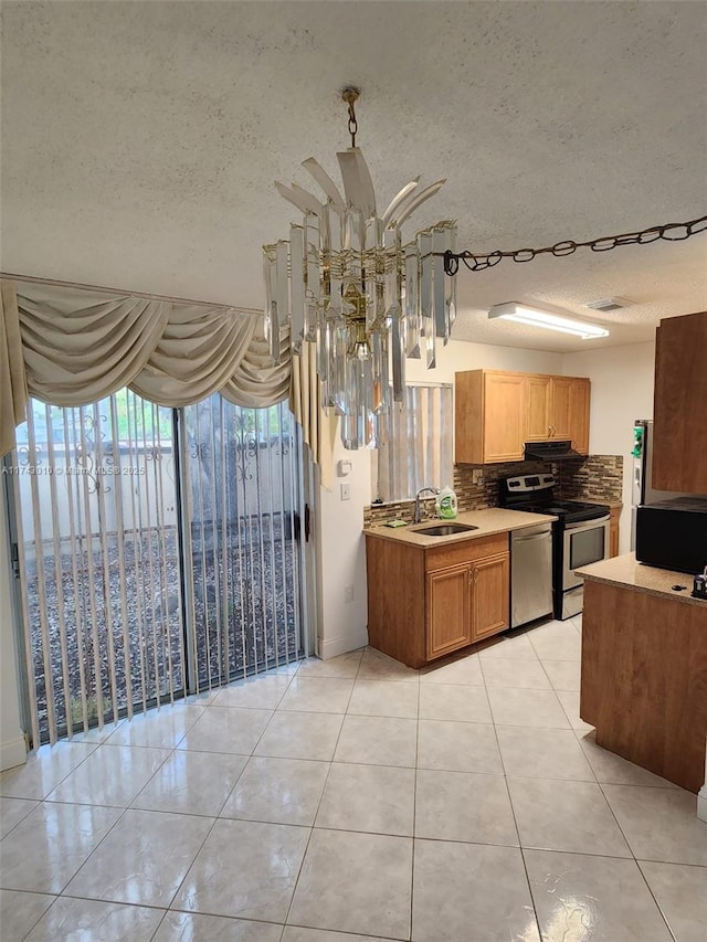 kitchen with light tile patterned flooring, sink, decorative light fixtures, stainless steel appliances, and backsplash