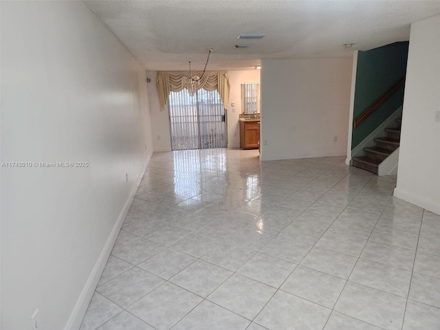 empty room with a textured ceiling and light tile patterned flooring