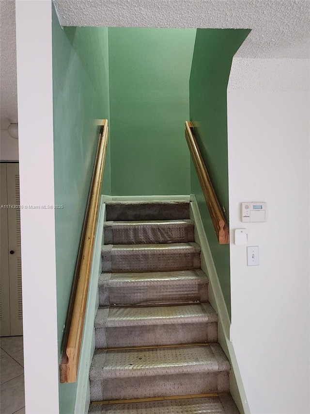 stairway with tile patterned flooring and a textured ceiling