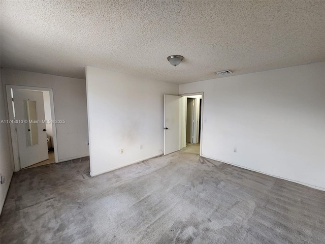 empty room with light colored carpet and a textured ceiling