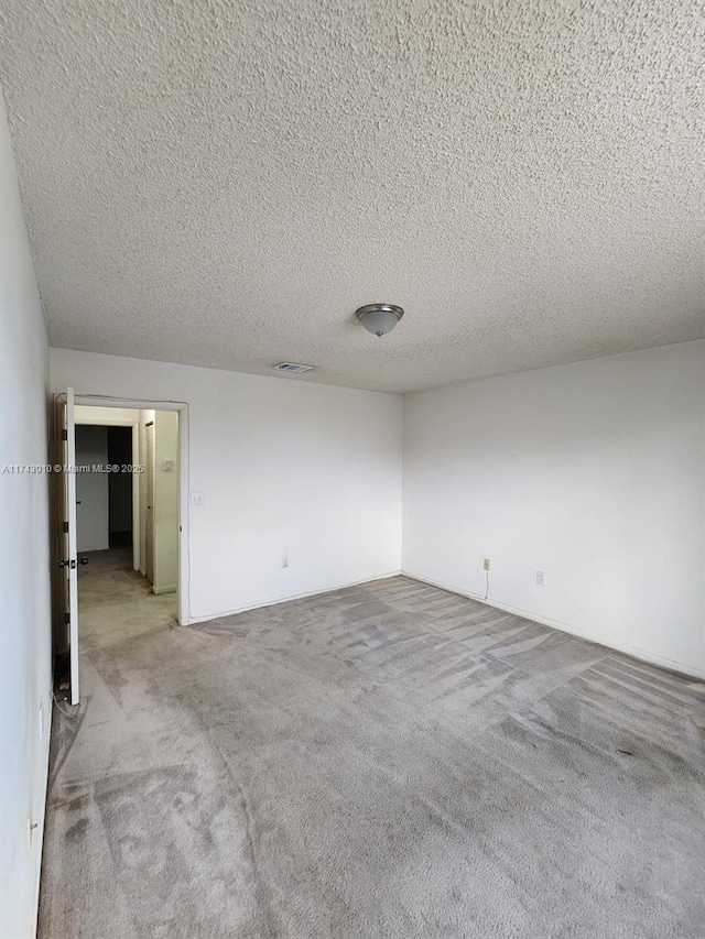 unfurnished room featuring light colored carpet and a textured ceiling