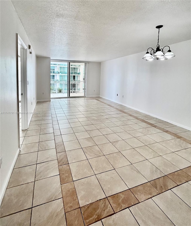 tiled spare room with expansive windows, a textured ceiling, and a notable chandelier