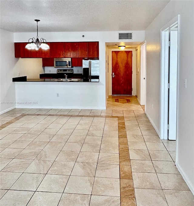 kitchen featuring hanging light fixtures, appliances with stainless steel finishes, light tile patterned floors, and a textured ceiling