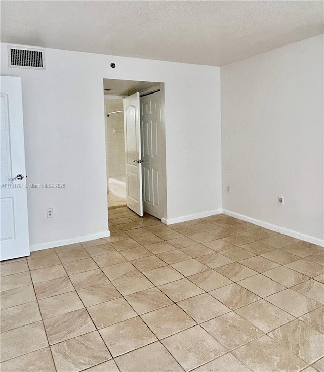 unfurnished room with light tile patterned flooring and a textured ceiling