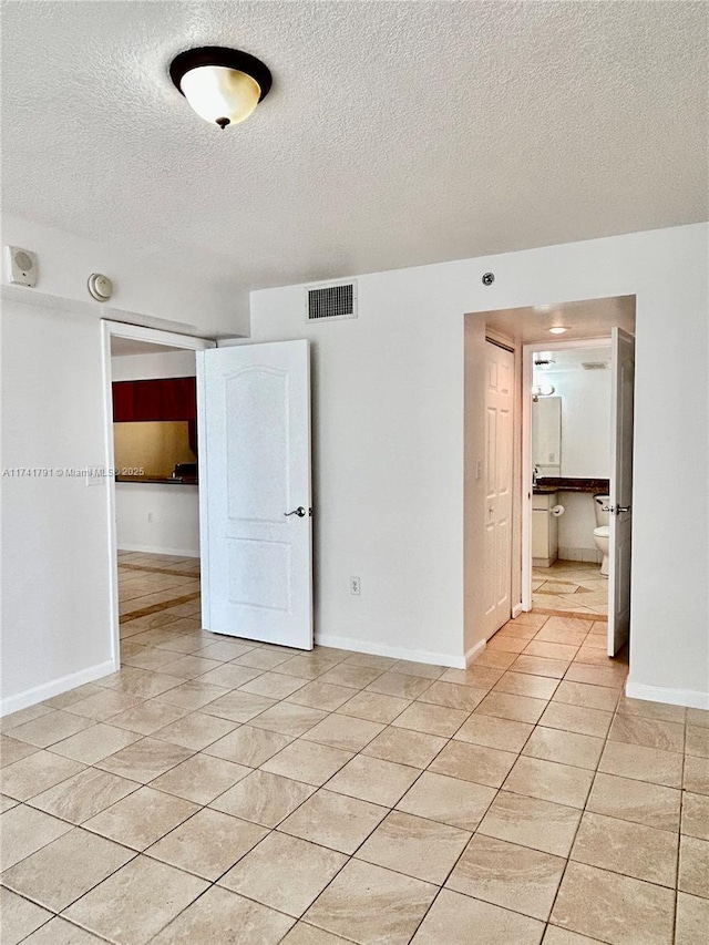 unfurnished room featuring a textured ceiling and light tile patterned flooring