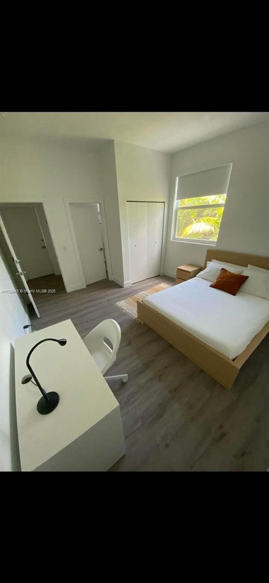 bedroom with dark wood-type flooring and a closet