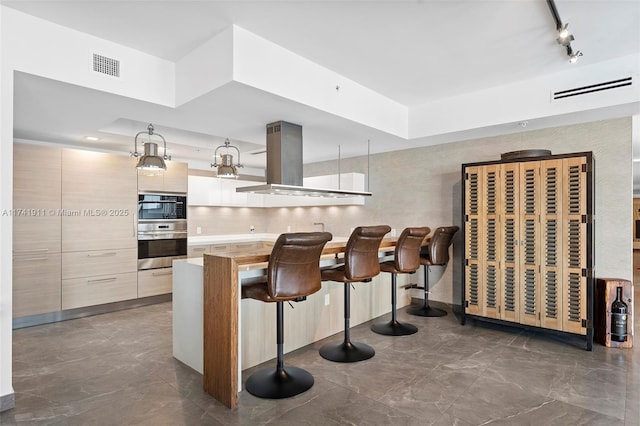 kitchen with pendant lighting, a breakfast bar, tasteful backsplash, island range hood, and kitchen peninsula