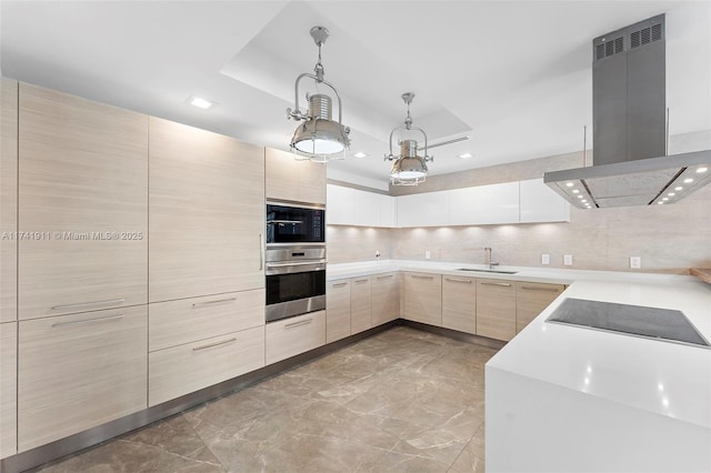 kitchen featuring light brown cabinetry, decorative light fixtures, a tray ceiling, island exhaust hood, and black appliances