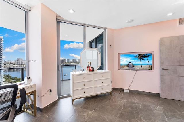 bedroom featuring a water view and a wall of windows