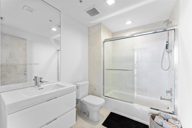 full bathroom featuring enclosed tub / shower combo, vanity, and toilet