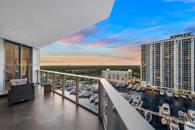 balcony at dusk featuring a water view