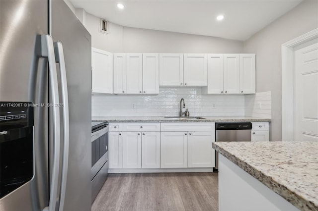 kitchen with white cabinetry, sink, light stone counters, and appliances with stainless steel finishes