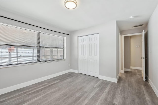 unfurnished bedroom with multiple windows, a closet, and light wood-type flooring